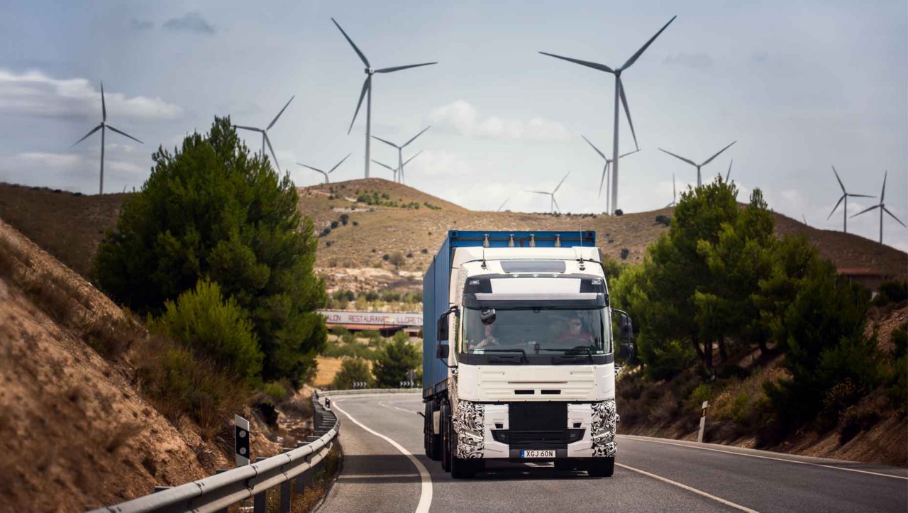 Тест камион на патот во Шпанија со ветерни турбини во позадина